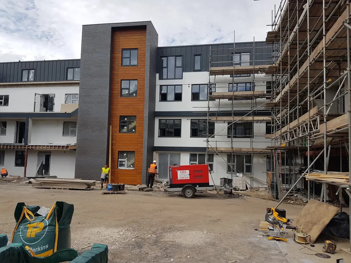 Modern apartment facade under construction with cladding, scaffolding and workers