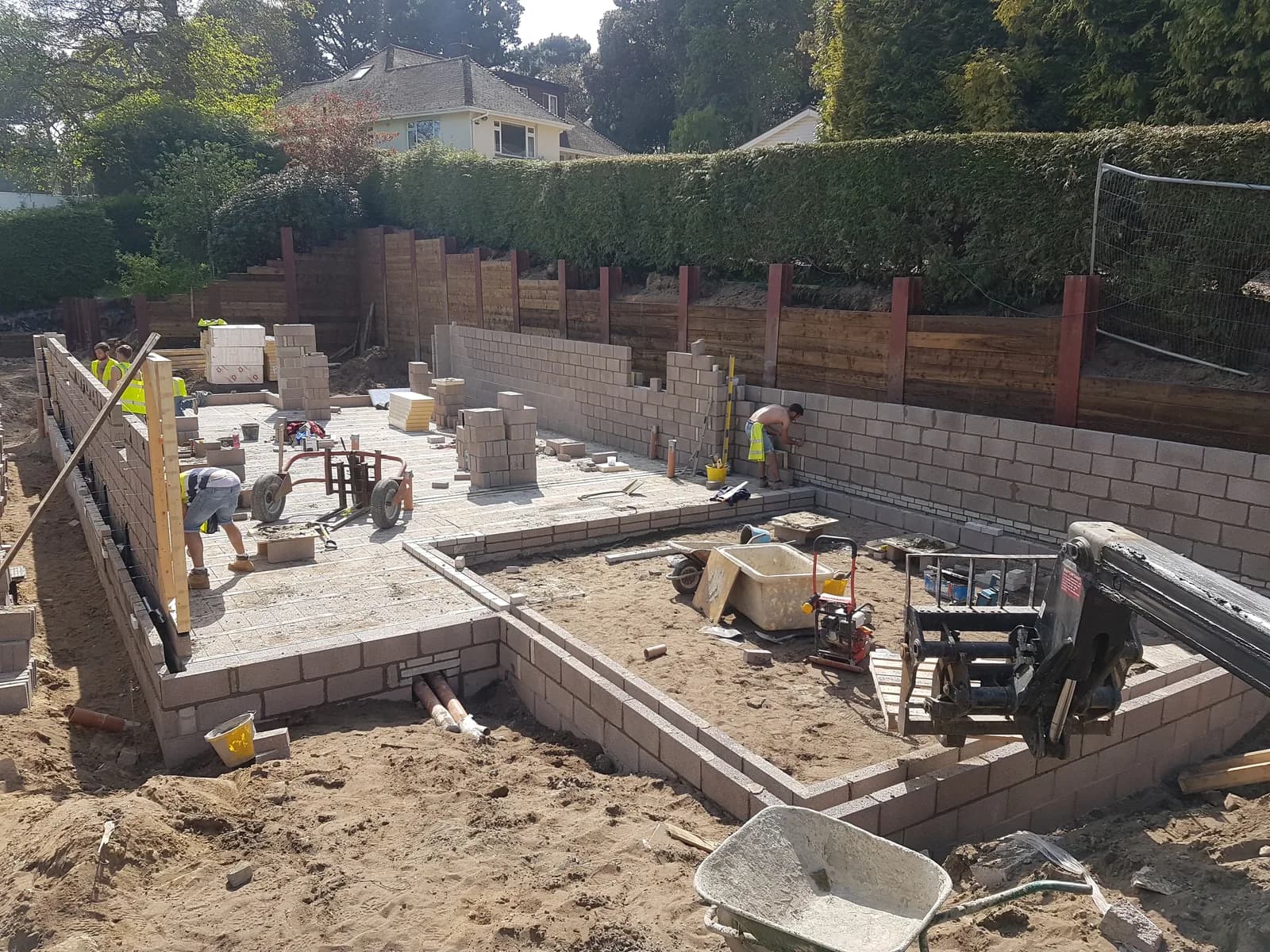 Workers building block walls inside a foundation footprint