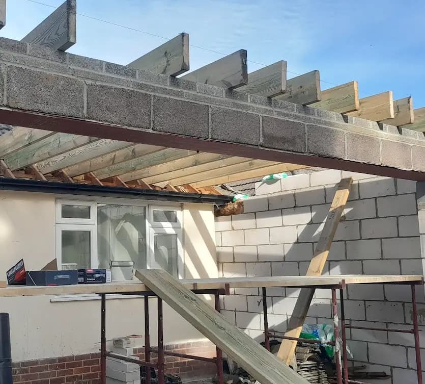 Concrete blockwork extension with timber roof joists and scaffold