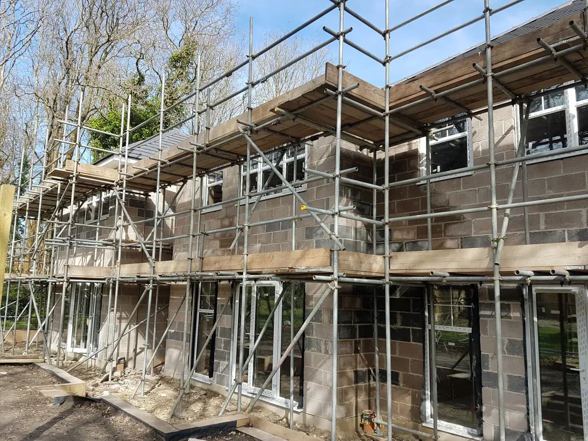 Blockwork building with new white-framed windows and surrounding scaffolding