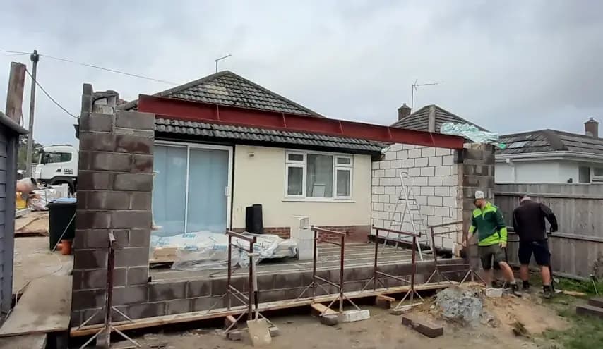 Bungalow extension with red steel beam, blockwork and workers on site