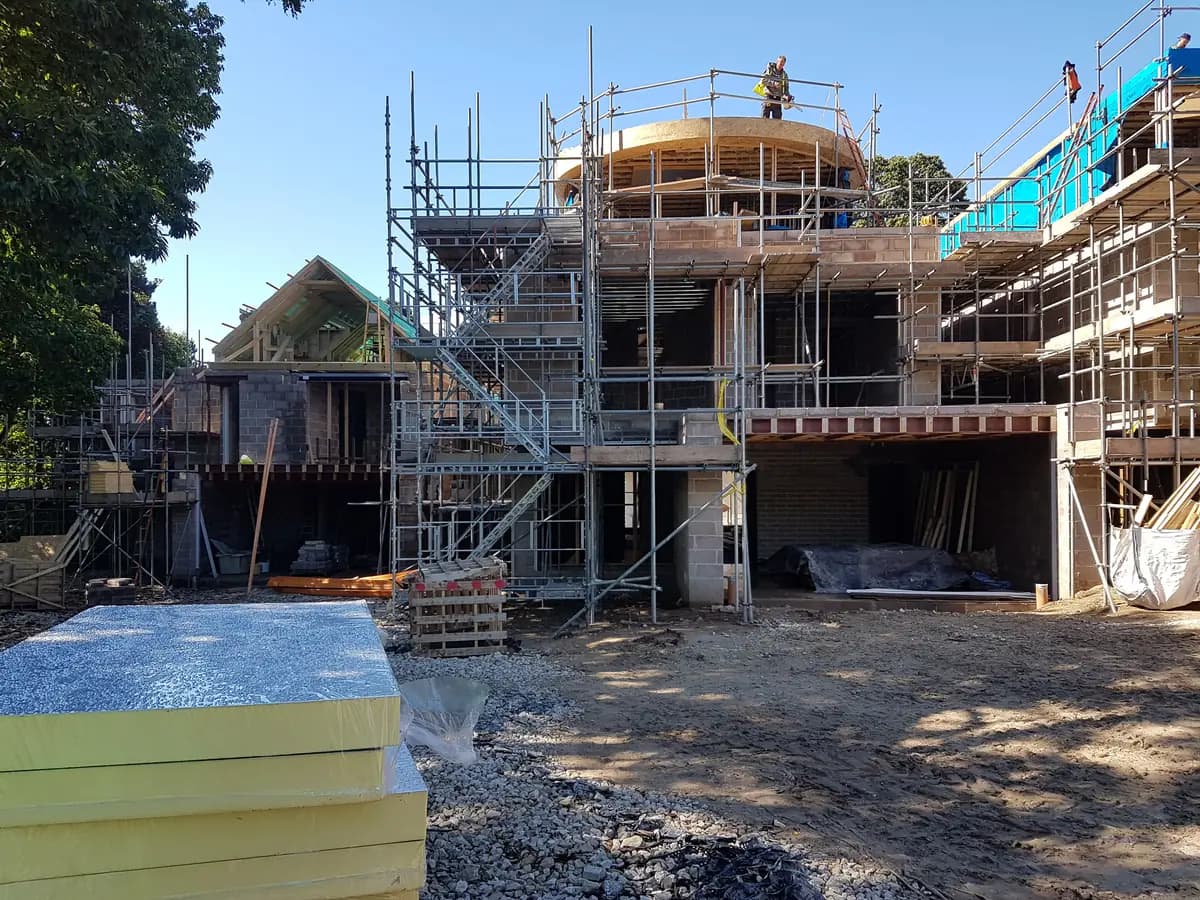 Curved timber roof structure with scaffolding and insulation boards on site
