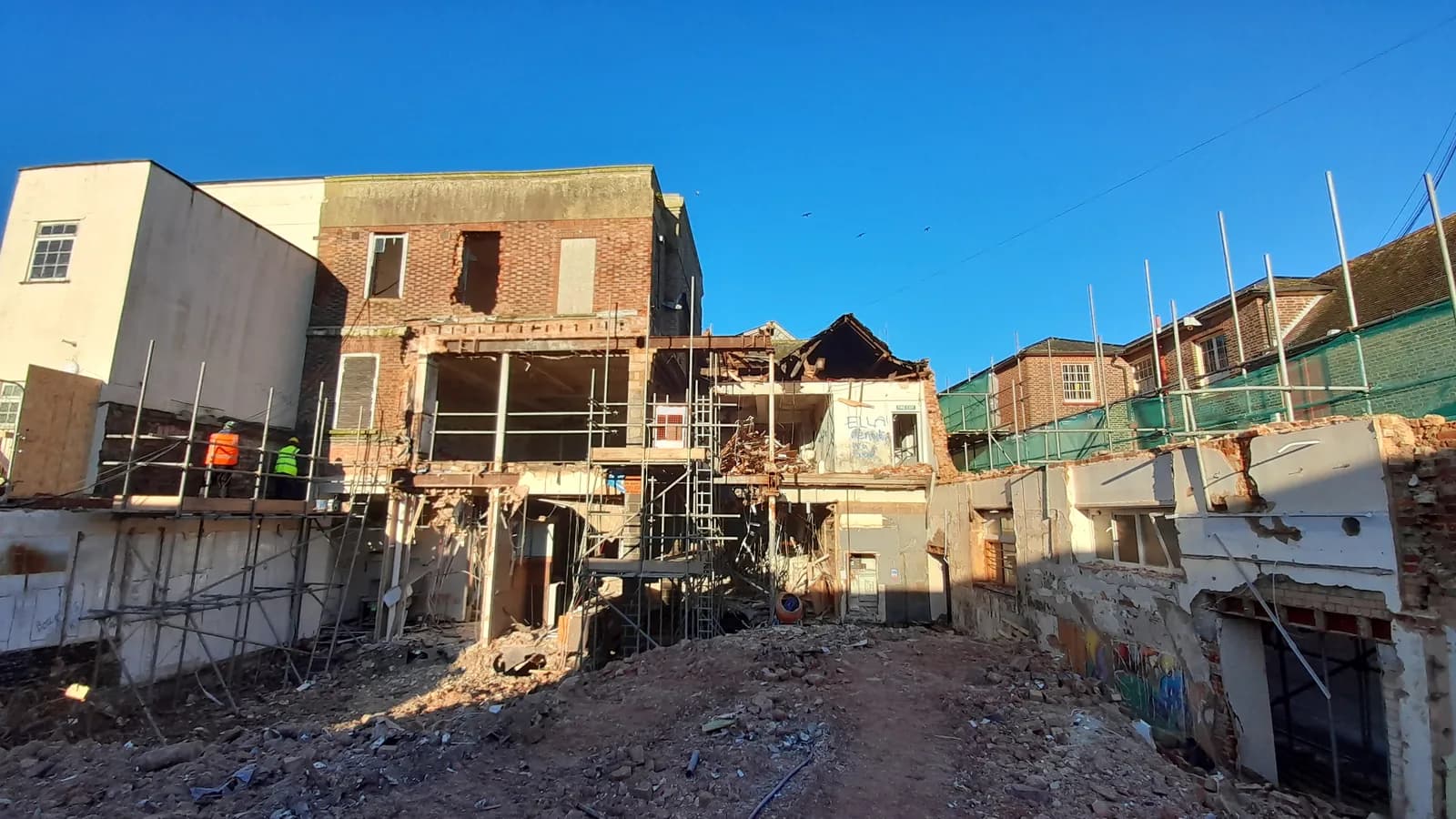 Demolition site with scaffold, rubble and exposed brick building