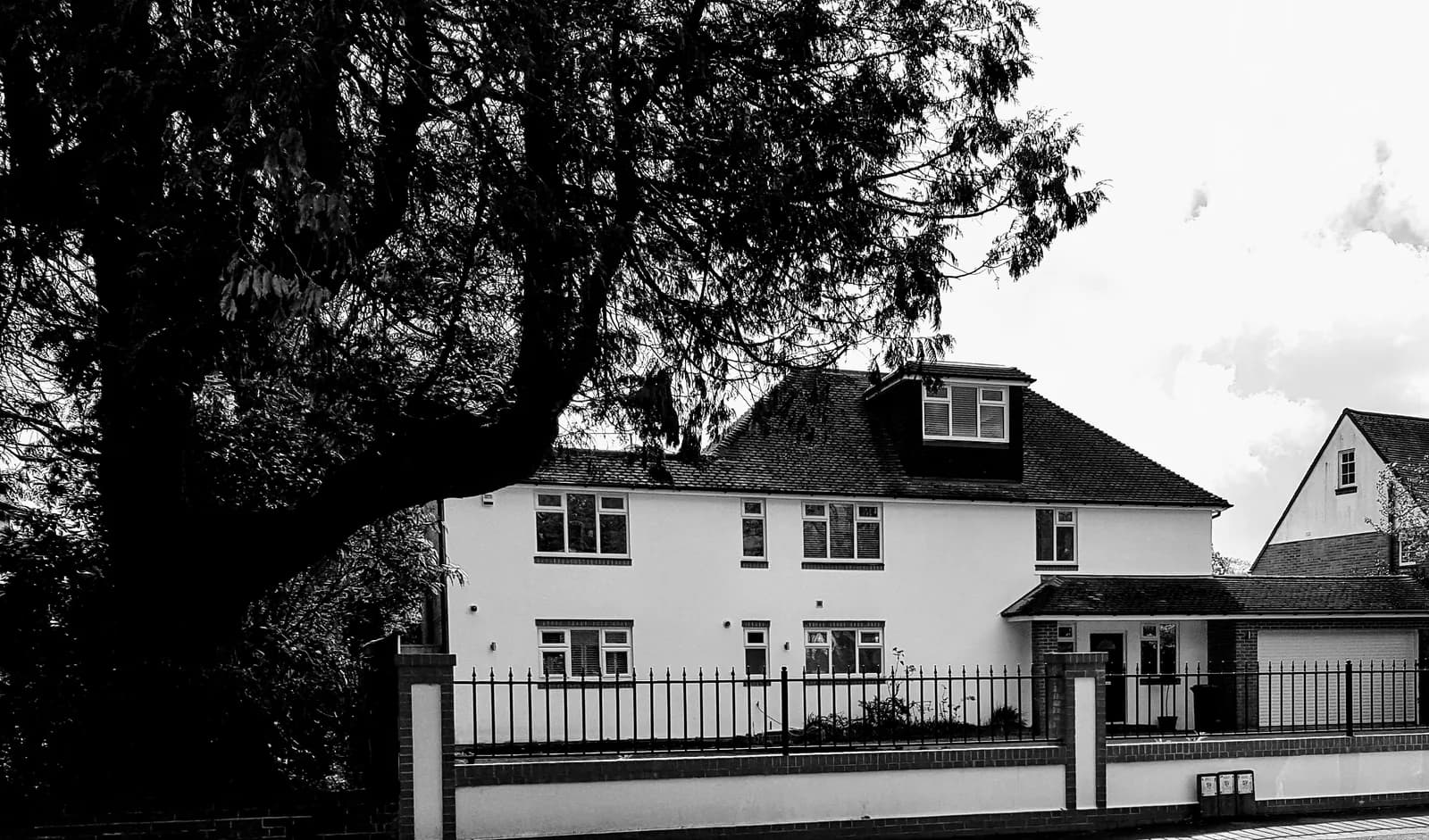 Detached residential property exterior with boundary wall and mature trees
