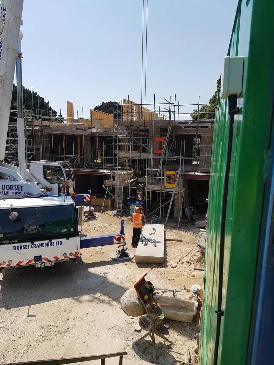 Mobile crane beside scaffolded masonry and timber frame structure
