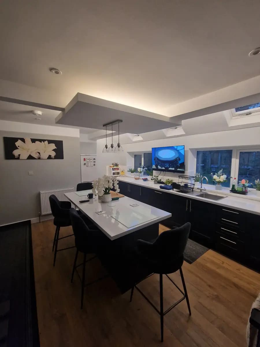 Modern kitchen interior with island, black cabinetry, rooflights and recessed lighting
