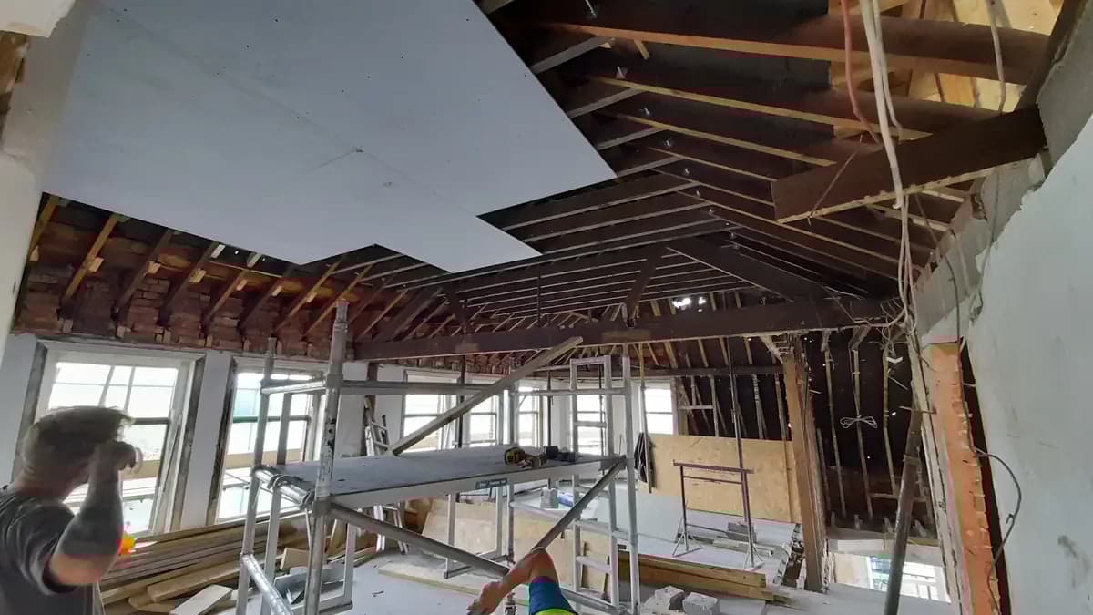 Interior renovation with exposed roof timbers, scaffold and partial plasterboard ceiling