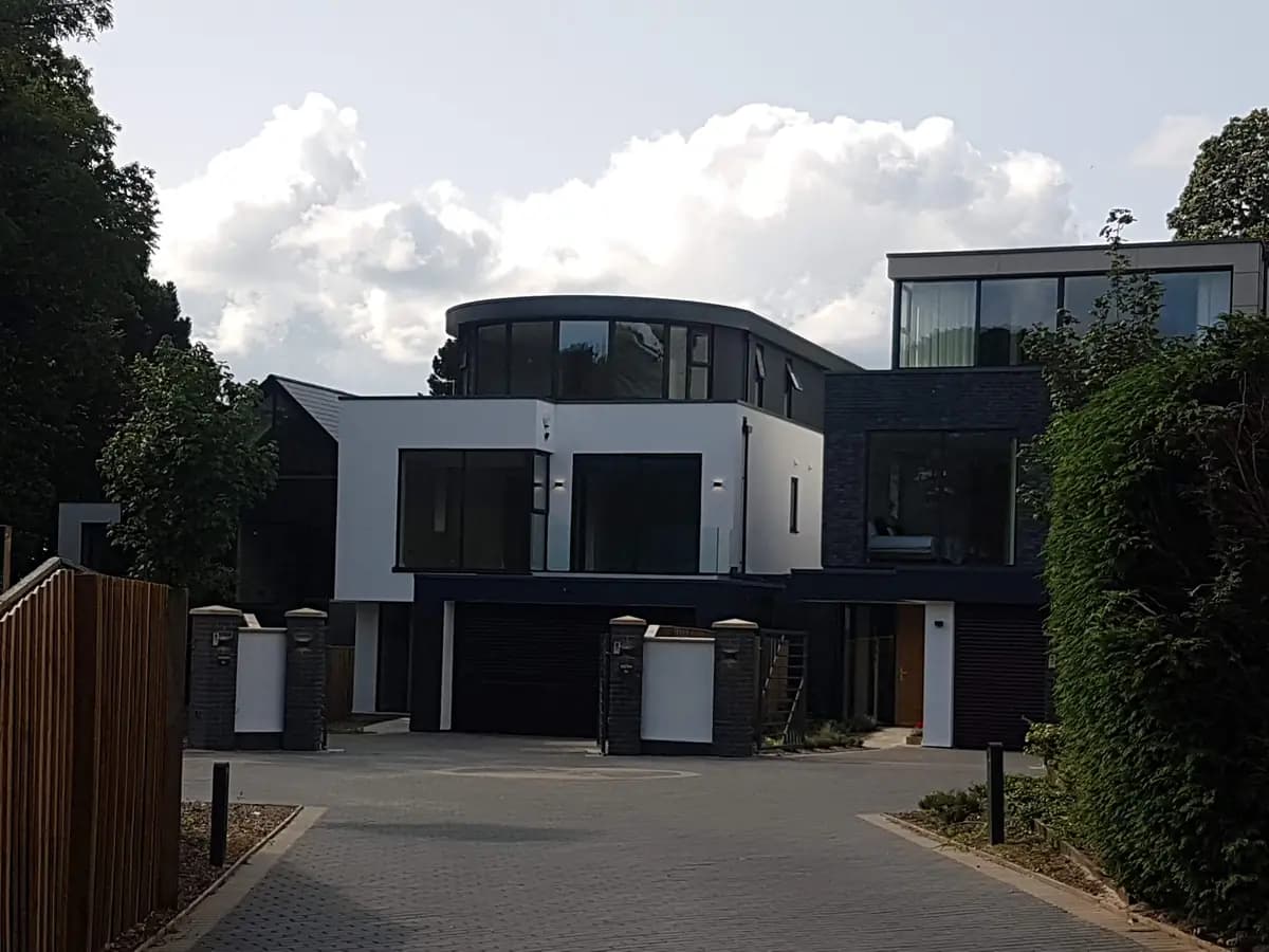 Modern white and dark house with curved window section and block-paved driveway