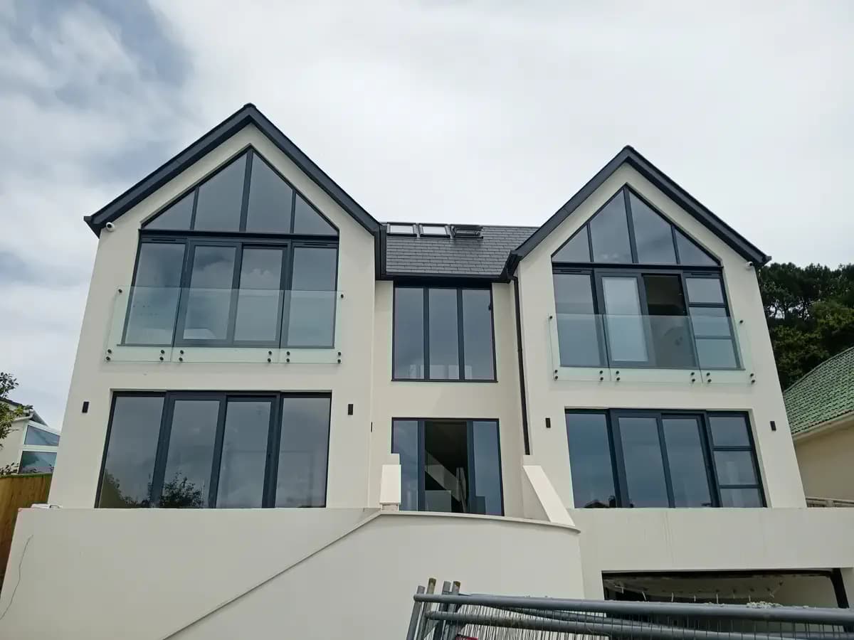 Modern cream house with gable glazing, glass balcony and dark roof trim