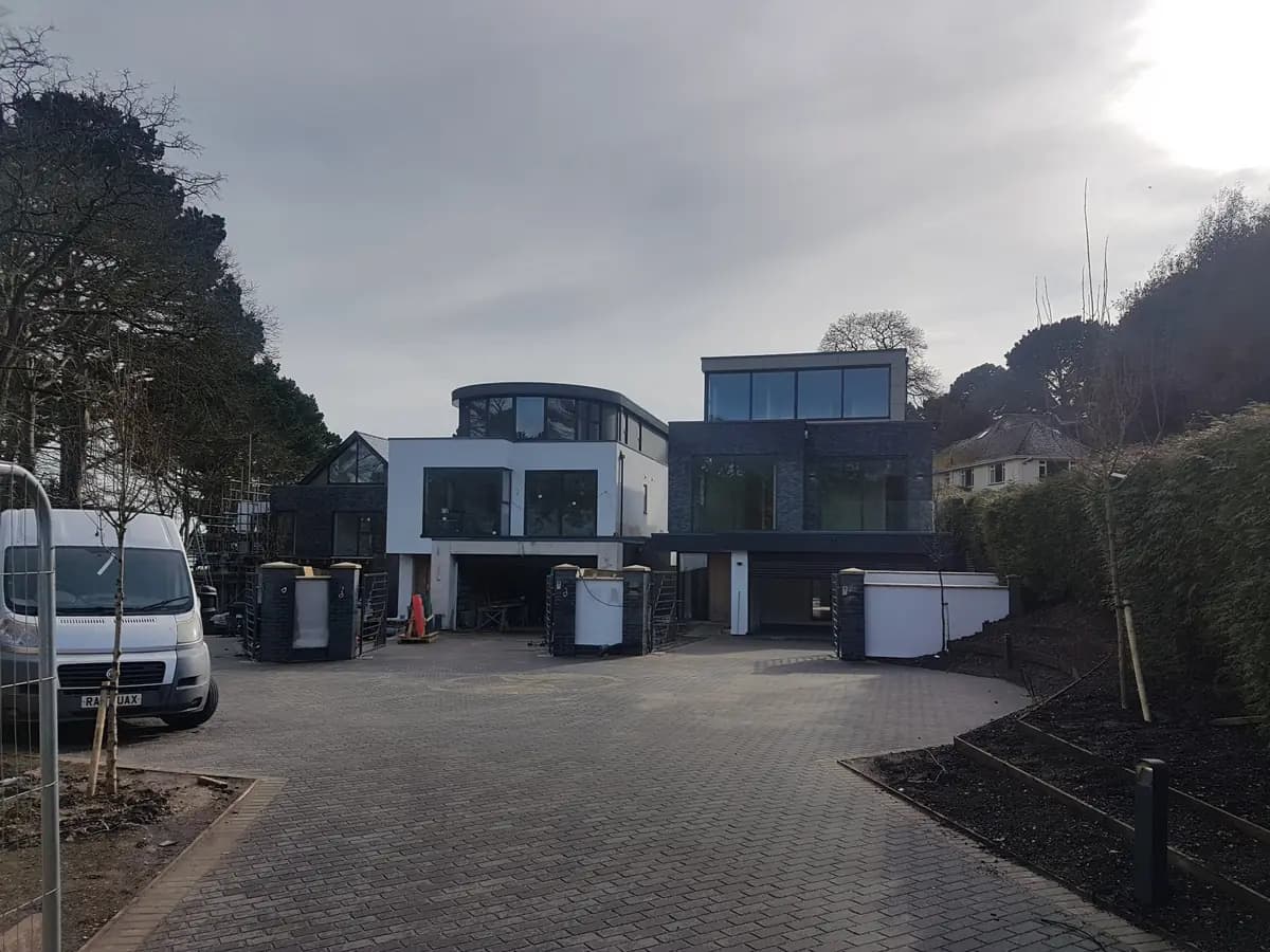 Modern house with block paved driveway, dark cladding and landscaped beds