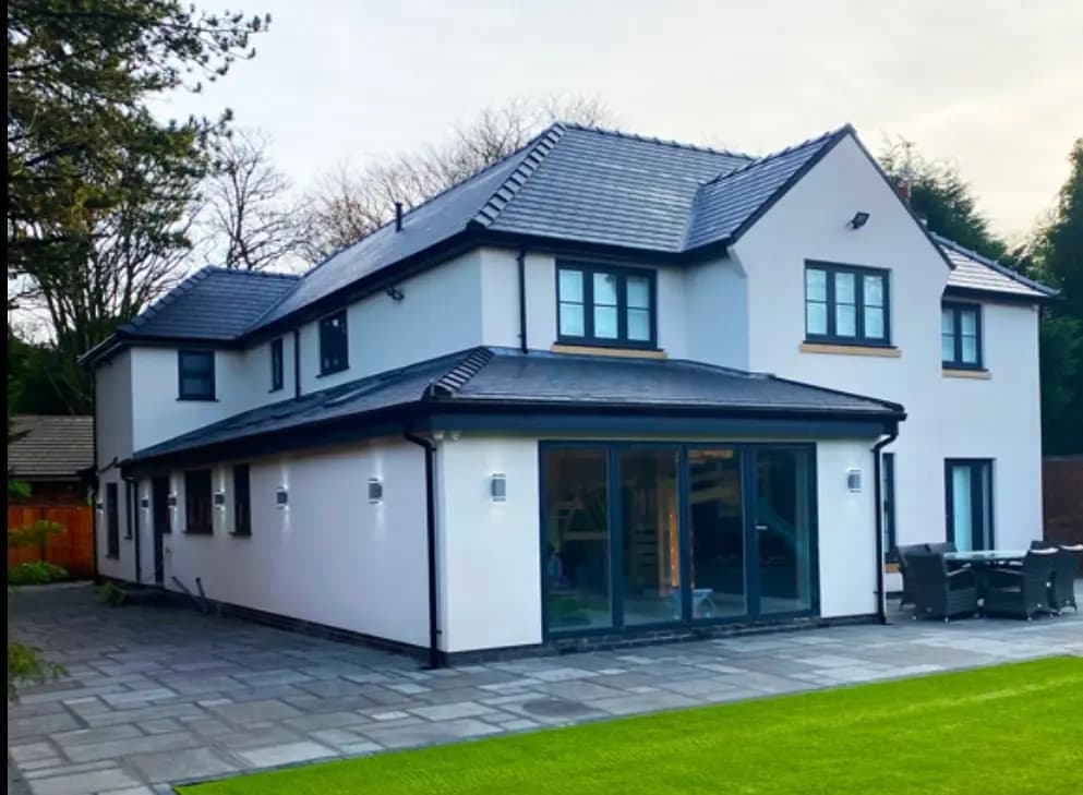 Modern rear house exterior with patio, lawn, bifold doors and garden seating