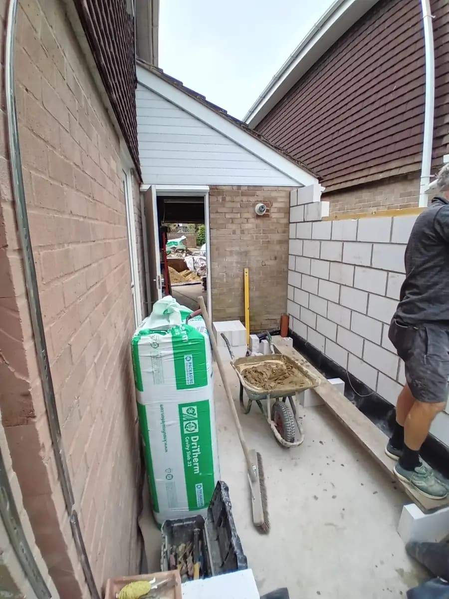 Narrow side passage with new block wall, insulation, mortar and tools