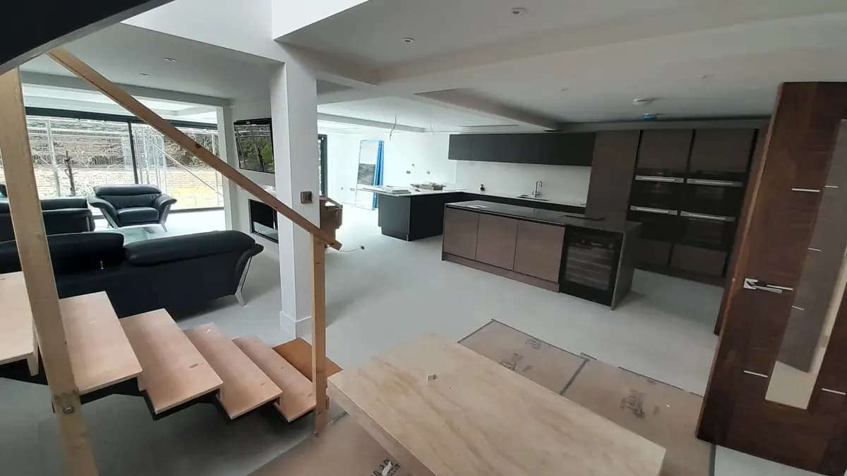 Open-plan kitchen and staircase under construction with temporary handrail