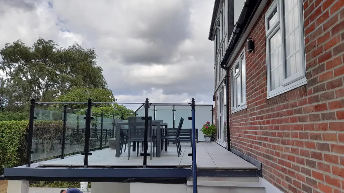 Brick house with raised tiled terrace, glass balustrade and patio furniture