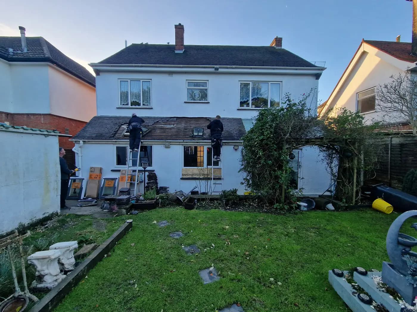 Residential rear roof refurbishment with workers, tiles and roof windows on site