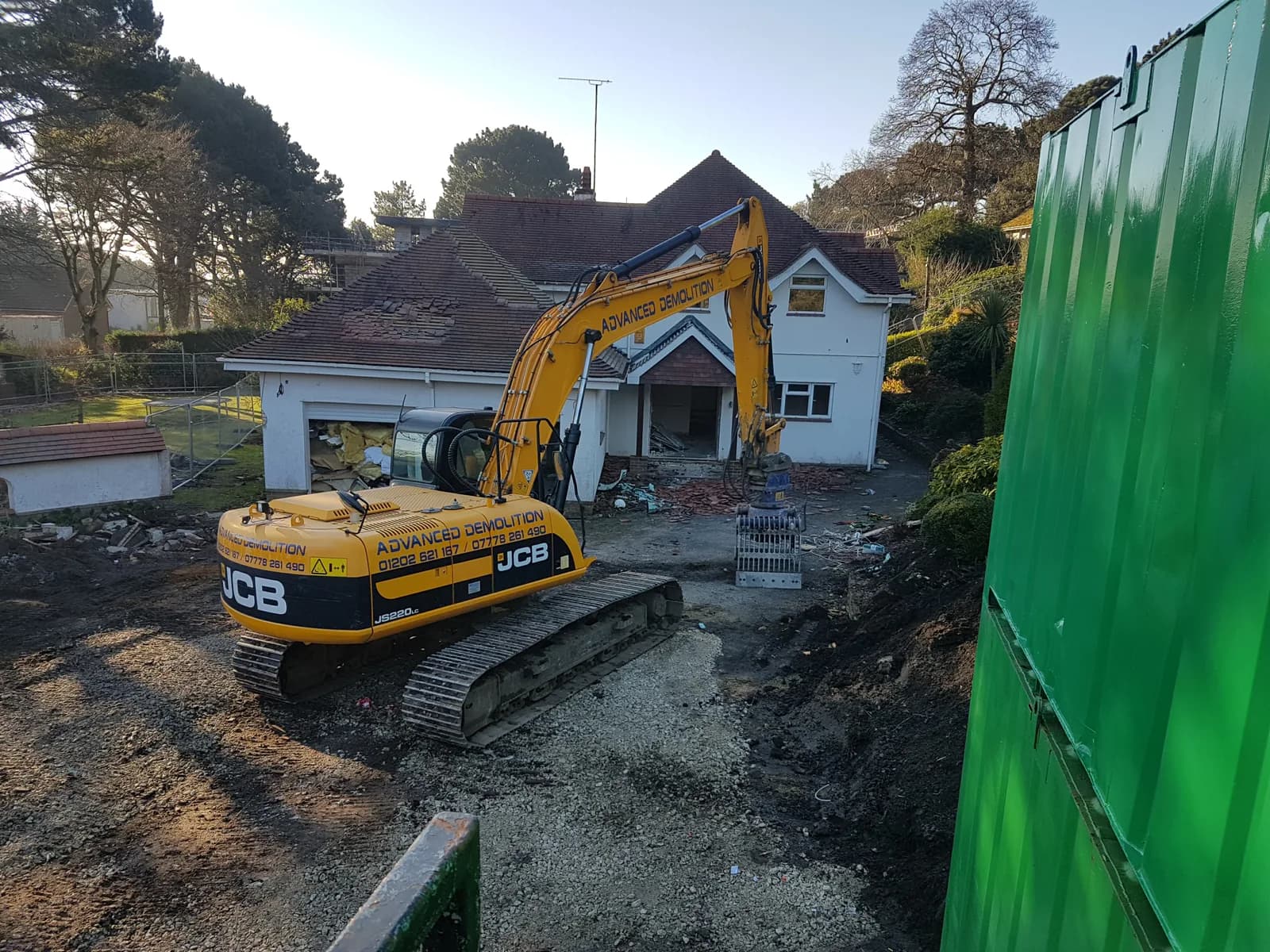 Excavator working beside a partially demolished residential building