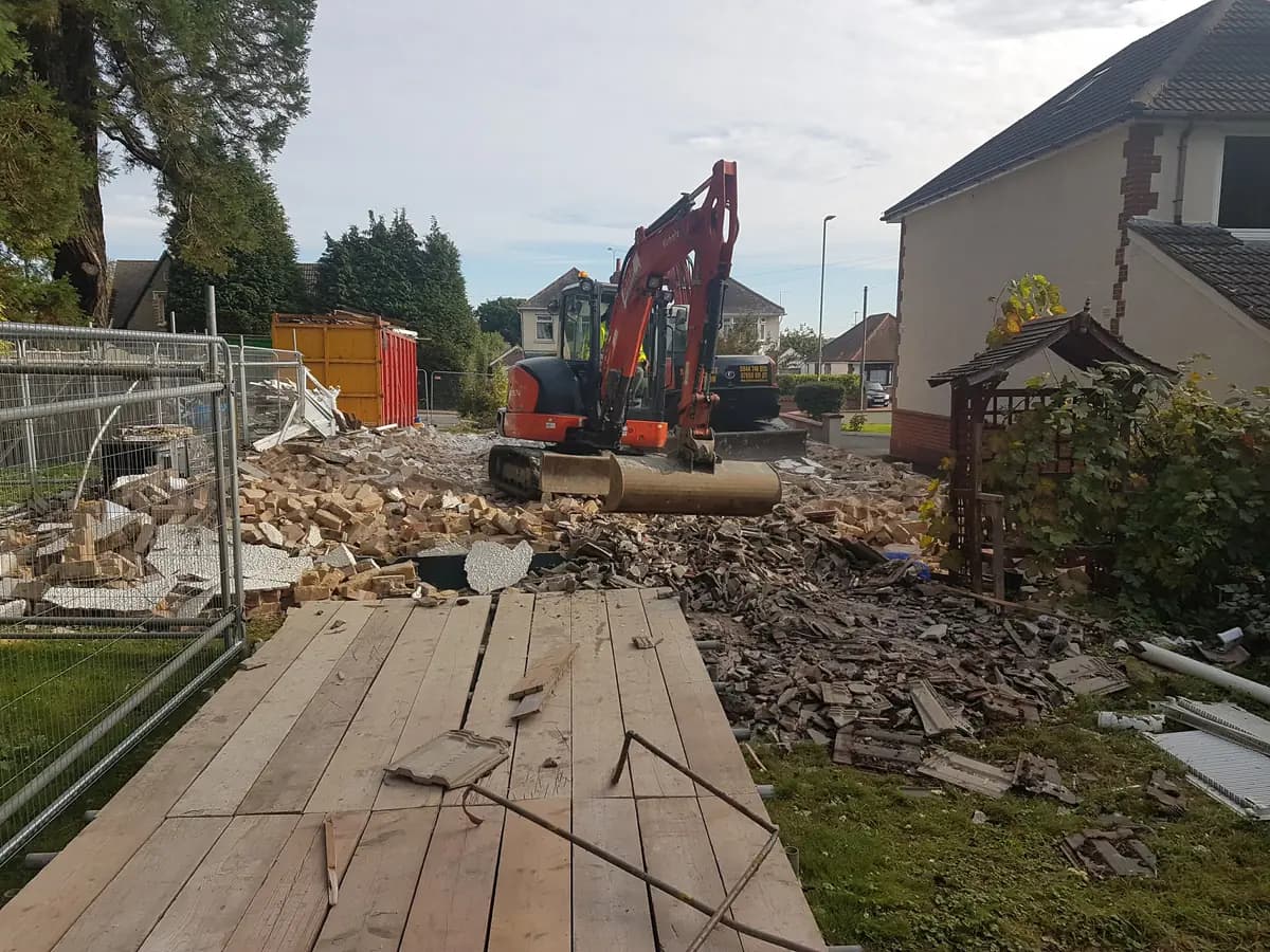 Residential demolition site with Kubota excavator, skip and rubble