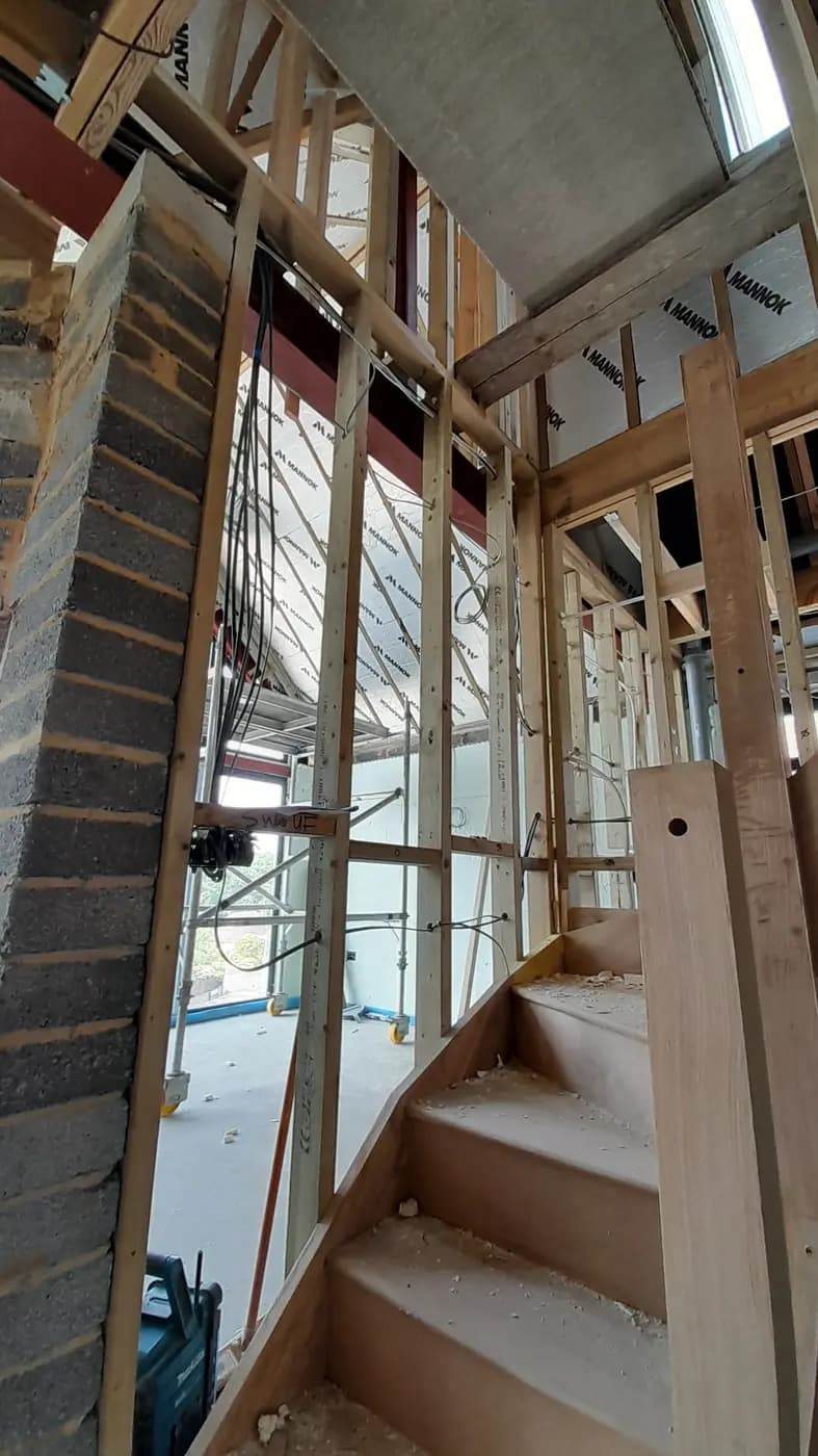 Unfinished interior staircase area with timber framing, scaffold and insulation