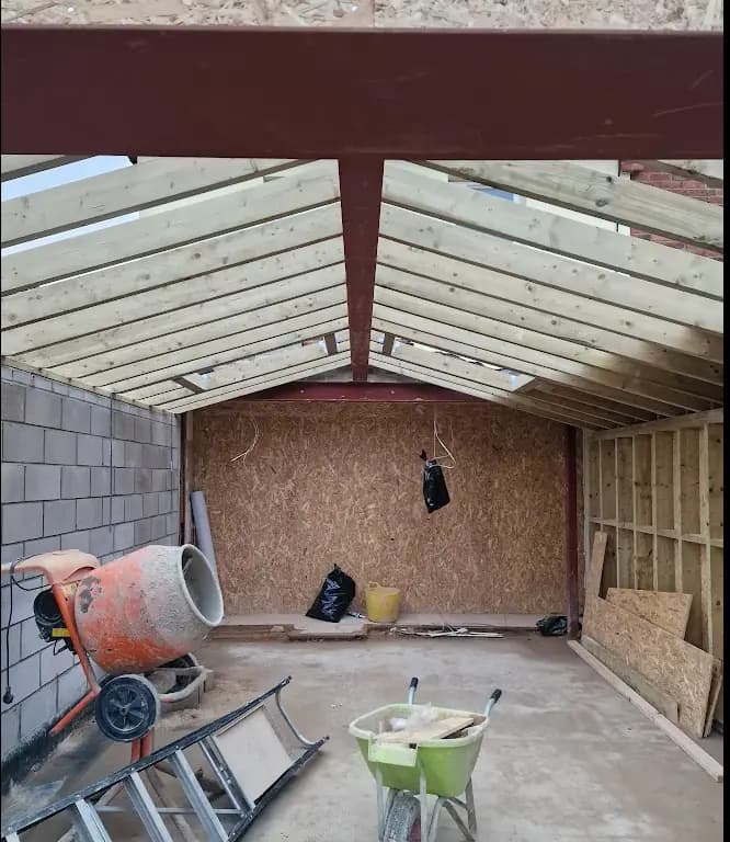 Timber roof framing with a red steel ridge beam inside a block and timber structure