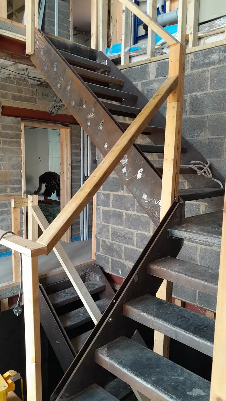 Dark steel staircase surrounded by timber framing and blockwork