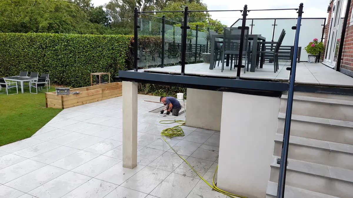 Terraced patio with glass railings, tiled steps, toolbox and worker