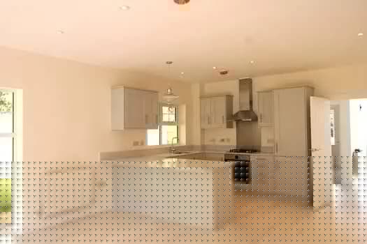 Bright modern fitted kitchen with white cabinetry, island, extractor and oven