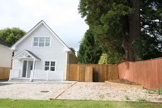 White-clad house with gravel driveway, timber fence and entrance porch