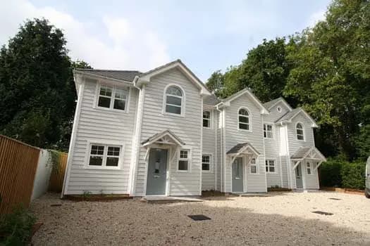 Row of white-clad townhouses with gravel driveway and porch canopies