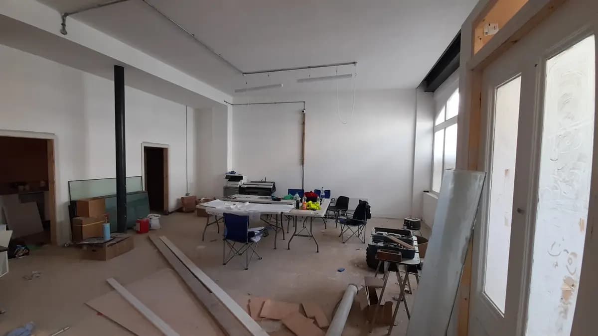 Large room under renovation with tables, tools, conduits and construction materials